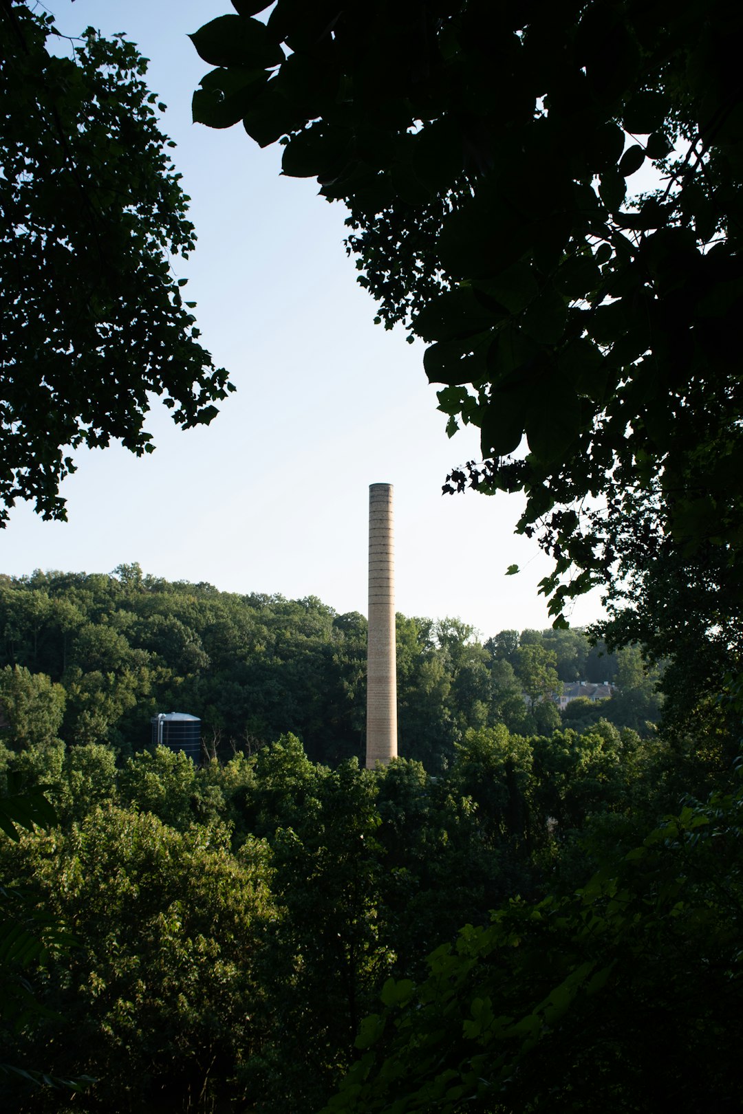 Historical Bancroft mills production industry factory smoke stack located in Wilmington Delaware at alapocas state park by History Hidden green trees under white sky during daytime
